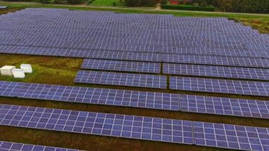 Güneş panellerinin sıraları yeşil alan boyunca uzanıyor, temiz enerji üretmek için güneş ışığını emiyor. Bu sürdürülebilir düzen modern teknolojinin doğayla uyum içinde olduğunu gösteriyor..