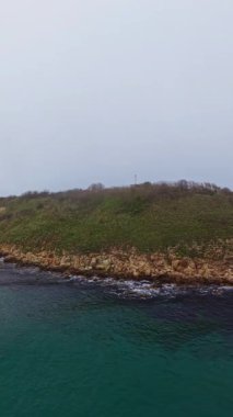 Gri bulutlar, berrak sulardan yükselen yeşil uçurumların üzerinde süzülüp yansıma ve doğa yürüyüşleri için mükemmel sakin ve manzaralı bir manzara yaratırlar..