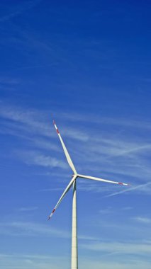 Bir çiftlikte rüzgar türbinleri çevre dostu bir elektrik santralinde yenilenebilir elektrik üretiyor. Mavi gökyüzüne karşı yel değirmenleri.