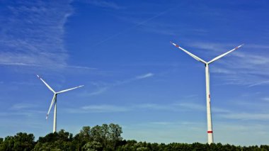 Rüzgâr türbininin parlak mavi gökyüzüne karşı dağınık bulutlu videosu. Yenilenebilir enerji yel değirmenleri tarafından üretilir. Mavi gökyüzüne karşı uzun yel değirmenleri.