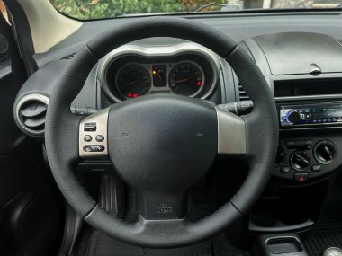 Direksiyonu, gösterge panelini ve göstergeleri gösteren bir arabanın iç tarafının yakın görüntüsü. Bu sahne, açık gökyüzünün altında neşeli bir yolculuk için bir anı yakalıyor..