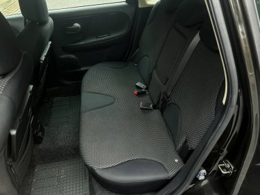 Yumuşak siyah kumaş, yolcuları rahatlatacak kompakt bir aracın arka koltuğuna dizilir. Sakin atmosfer, hareketli bir şehir manzarasında rahatlatıcı bir yolculuğa işaret ediyor..