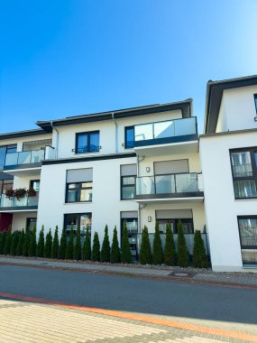 Parlak ve davetkar, bu çağdaş evler gösterişli balkonlar ve bakımlı bahçeler içeriyor, banliyö ortamında uyumlu bir atmosfer yaratıyorlar..