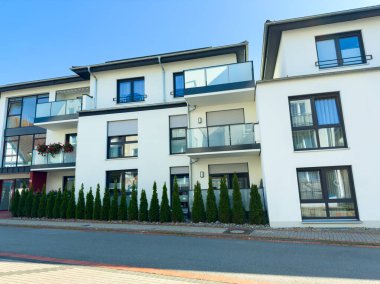 İki farklı apartman dairesi gösterişli mimari, büyük pencereler ve parlak balkonlar. Uzun çalılar caddeyi kaplıyor. Açık bir günde bu huzurlu şehir ortamına cazibe katıyor..