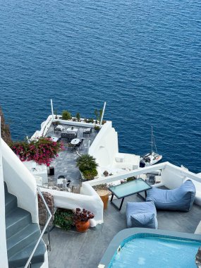 Bu sakin teras şık oturma ve gür çiçekleri barındırıyor, derin mavi denize bakıyor, dinlenmek için mükemmel sakin bir atmosfer yaratıyor..