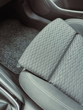 Bir araba koltuğunun yakın plan görüntüsü kumaş tasarımını gösteriyor, yumuşak bir şekilde aydınlatılıyor, aracın iç mekanının temiz ve modern estetiğini vurguluyor..