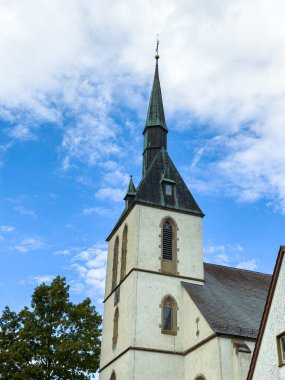 Gökyüzüne uzanan yüksek kulesiyle gururla ayakta duran büyüleyici bir kilise. Güçlü mimari çizgiler parlak mavi arkaplan ve ince bulutlarla çok güzel tezat oluşturuyor..