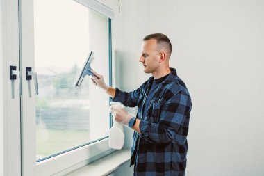 Detaylara odaklanarak, bir adam pencereyi temizlemek için cam sileceği kullanır ve doğal ışığın odayı aydınlatmasına izin verir. Dikkatli tekniği kusursuz bir son vaat ediyor..