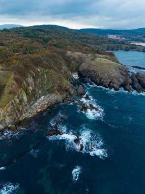 Nefes kesen uçurumlar engin okyanusa bakar. Güneş batarken dalgalar yavaşça kayalık kıyıya çarpar ve kıyı manzarası arasında sakin bir atmosfer yaratır..