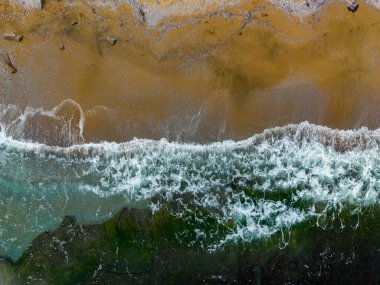 Güneşli bir öğleden sonra okyanusun parlak turkuaz dalgaları ile altın kum arasındaki zıtlığı gösteren çarpıcı bir hava perspektifinin keyfini çıkarın..