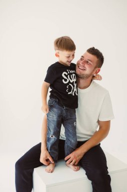 Minimalist bir stüdyoda, bir baba ve oğul gerçek kahkahaları paylaşıyor, aile bağlarının ve birlikte yaratılan neşeli anıların derin güzelliğini vurguluyorlar.