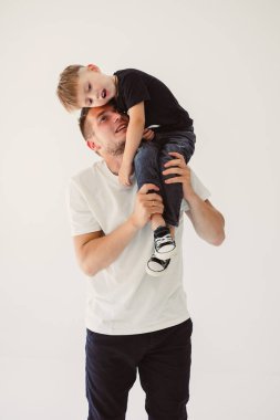 Mutlu ve gururlu bir baba, neşeli ve sıcak bir stüdyoda saf mutlulukla dolu, yürek ısıtan, unutulmaz bir anı yakalayarak, güler yüzlü çocuğunu omuzlarına alır.