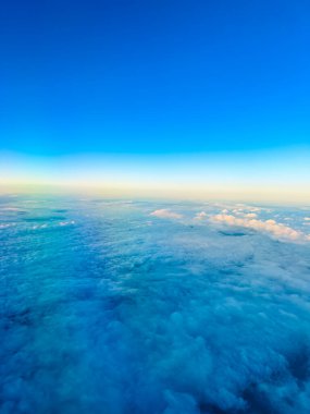 Parlak mavi gökyüzü, okyanusun üzerinde alacakaranlıkta kabarık beyaz bulutlarla karşılaşır. Manzara mavi ve beyaz tonlarını gösteriyor. Ufuk çizgisi yumuşak..