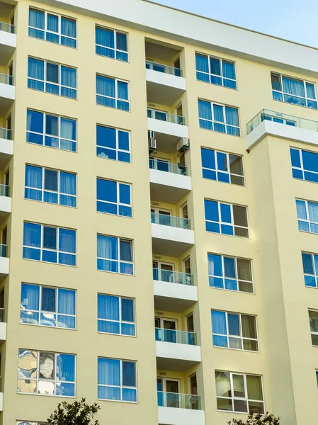 Yüksek bir binanın birçok katı vardır, her birinin birden fazla penceresi vardır. Pencereler gökyüzünü ve yakınlardaki manzarayı yansıtıyor. Sahne açık gökyüzünün altındaki bir şehir bölgesinde geçiyor..