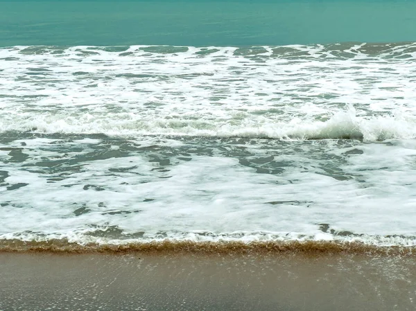 İnsanlar yakınlarda yürürken dalgalar kumsala vuruyor. Güneş ışıl ışıl parlıyor ve su berrak gökyüzünün altında parlıyor. Okyanusta keyifli bir gün ziyaretçileri sahilin tadını çıkarmaya davet eder..