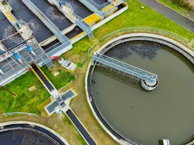 Su arıtma tesisi büyük dairesel tankların atık suyu tedavi ettiğini gösteriyor. Makineler ve yürüme yolları bu süreçte yardımcı olur. Bölge iyi organize edilmiş ve temiz..