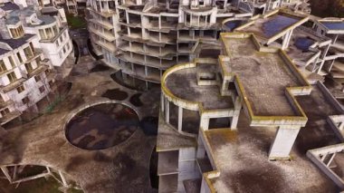 Hava manzarası terk edilmiş binaların karmaşık formlarını yakalıyor, yıpranmış yüzeylerini ve dengesiz seviyelerini gösteriyor. Issız bir ortamda unutulmuş bir tutkunun akılda kalıcı bir hatırlatıcısı..