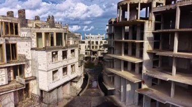 Boş yapılar sessizce duruyor, eksik formları hayaller ve hırslar hakkında hikayeler anlatıyor. Zaman, unutulmuş umutların çatlaklarından geçerken doğa mekanı geri almaya başlar..