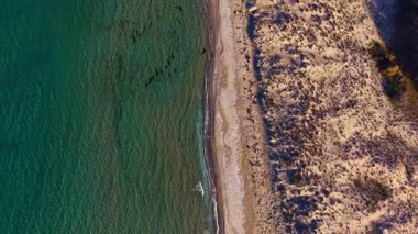 Açılmış manzara, altın kum ve seyrek yeşillikle çevrili, sakin dalgaların kıyıları öptüğü, keşif ve rahatlamaya davet ettiği sakin bir sahili gözler önüne seriyor..