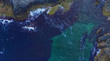 Dalgalar, parlak mavi ve parlak yeşilliklerin güneş ışığında çarpıcı bir duvar halısı oluşturduğu canlı kayalık bir sahil şeridini nazikçe siler. Yazın huzuru bizi çağırıyor..