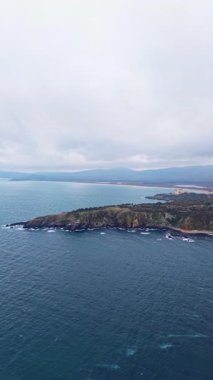 Yuvarlanan dalgalar bulutlu bir gökyüzünün altında sakin bir kıyı şeridi gibi kayalık kıyılara doğru yavaşça süzülüyor. Sahne huzur, yansıma ve keşiflere davetiye çıkarıyor..