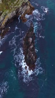 Gün batımında parlak dalgalar pürüzlü kayalara doğru akın ederek derin mavi su ile engebeli kıyı şeridi arasında çarpıcı bir kontrastlık yaratır. Doğanın güzelliği sergileniyor.