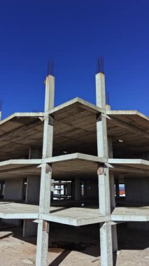 Beton sütunlar açık mavi gökyüzüne doğru yükselirken işçiler şehir manzarasını geliştirmek için inşa etmeye devam ediyorlar. Dayanıklı çerçeve gelecekteki büyümeyi ima eder.