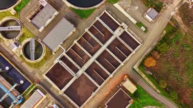 Hava görüntüsü, yeşil çevre ve açık mavi gökyüzü arasında işlenen ve su yönetimi ihtiyacını vurgulayan büyük bir atık su arıtma tesisi gösteriyor..