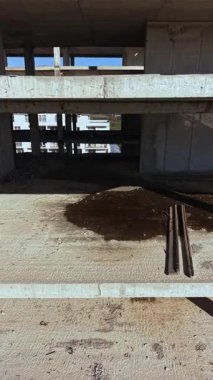 Toz ve enkaz, bu şehrin geleceğini şekillendirmek için devam eden çabaları ima ederek paslı çubukların karanlık bir yamanın yanında durduğu bir inşaat alanının bitmemiş zeminini dağıtıyor..