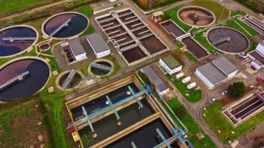 Atık suyu etkili bir şekilde işlemek ve arıtmak için tasarlanmış çoklu dairesel tanklar, filtreleme sistemleri ve kontrol binalarının yer aldığı bir su arıtma tesisinin kapsamlı bir görüntüsü.