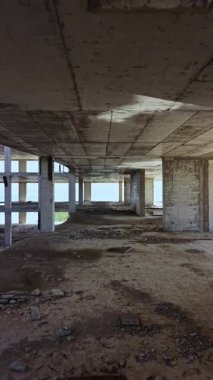 Güneş ışığı terk edilmiş beton bir binanın açık alanlarında akar tozlu zemine gölgeler bırakır. İnşaatın kalıntıları açık iç kısımları çevreleyerek ihmalkarlığa bir bakış sunuyor..