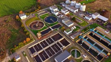 Havadan bakıldığında, bereketli yeşilliklerin yanında işleyen bir atık su arıtma tesisi, dairesel tanklar, büyük binalar ve su arıtma için gelişmiş teknolojiye sahip bir atık su arıtma tesisi görülüyor..