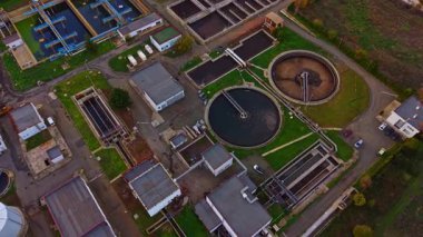 Hava görüntüsü, yeşil bir çevrede su arıtma ve geri dönüşümün önemini vurgulayan büyük tankları ve boruları olan bir atık su arıtma tesisini ortaya çıkarıyor..