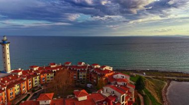 Büyüleyici sahil kesiminde kıyı boyunca yuva yapmış kırmızı çatılı renkli evler yer alıyor. Sakin deniz, nefes kesici bir akşam gökyüzünün altında parıldıyor, manzaranın güzelliğini zenginleştiriyor..