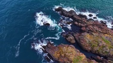 Güçlü dalgalar kayalık oluşumlarla çarpışır ve açık mavi gökyüzünün altında havaya deniz püskürtüsü gönderir. Vahşi güzellik ve doğa bu sakin kıyı bölgesinde gelişir..