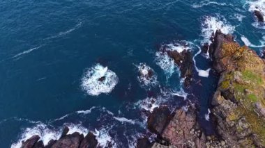 Güneş doğarken dalgalar çarpıcı uçurumlara çarpar. Karanlık suları ve kayalık kıyıları aydınlatır. Doğanın ham enerjisinin çarpıcı bir görüntüsüyle..