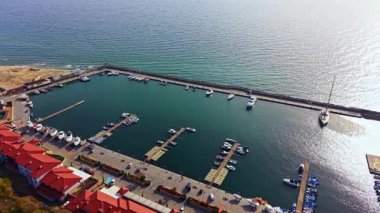 Havadan bakıldığında huzur içinde dinlenen çeşitli teknelerle dolu sakin bir liman görülüyor. Güçlü rıhtımlar sakin sulara doğru uzanır, yumuşak güneş ışığını yansıtırken, yakınlardaki binalar cazibe katar..