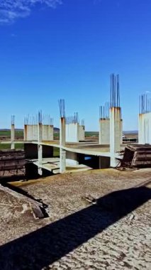 Beton sütunlar, terk edilmiş bir inşaat projesini gözler önüne seren çarpıcı bir mavi zemine çarpıyor. Aşırı gelişmiş doğa, doğanın ıslah edilişine işaret ediyor..