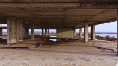 Issız bir binada, harap olmuş beton ve paslanmış kirişler, batan güneş sakin sulara ve yemyeşil tepelere yumuşak bir ışık saçarken ürkütücü bir atmosfer yaratıyor..