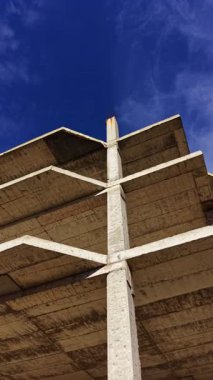 Çağdaş mimari tasarımın yaratıcılığını ve karmaşıklığını gözler önüne seren, canlı mavi gökyüzüne karşı, hassas çizgiler ve açılarla yukarıya doğru uzanan beton bir yapı..