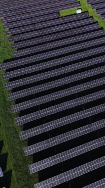 Güneş panelleri, açık mavi gökyüzü altında temiz enerji üretmek için güneş ışığını yakalayarak yeşil bir alan boyunca uzanıyor. Sahne yenilenebilir enerjideki yenilikleri vurguluyor.