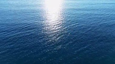 Okyanus suyunun dalgaları parlak güneş ışığı altında parıldıyor, parlak bir parıltıyı yansıtıyor. Sahne sakin bir öğleden sonra sükunetin ve güzelliğin özünü yakalar..