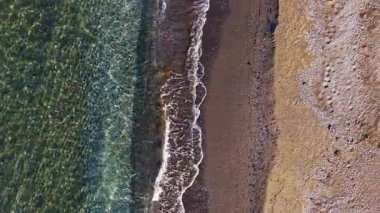 Yumuşak dalgalar kıyı şeridine yuvarlanarak rahatlatıcı bir ritim yaratıyor. Güneş ışığı berrak suda parıldıyor kumsalın kumlu renkleriyle harmanlanıyor ve sükuneti davet ediyor..