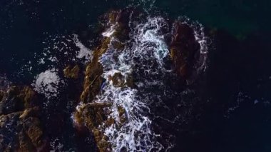 Okyanus dalgaları güçlü kayalara karşı güçlü bir şekilde yuvarlanarak güneş ışığında güzel bir beyaz köpük oyunu yaratır. Doğa gücünü ve güzelliğini bu kıyı sahnesinde sergiliyor..