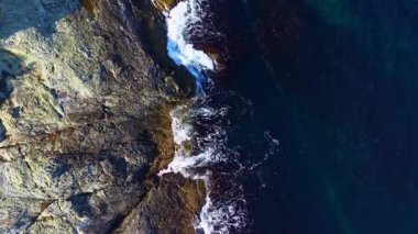 Kayalık uçurumlar okyanusla canlı bir günbatımının altında karşılaşıyor. Dalgalar acımasız bir şekilde kıyıya çarpıyor. Doğanın gücünü ve huzurunu mükemmel bir uyum içinde sergiliyor..