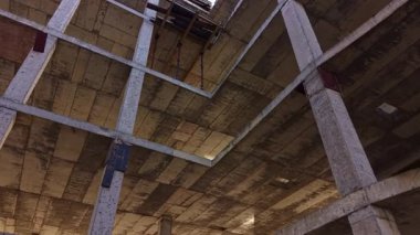 Bir inşaat sahasının iskelet çerçevesi arasında, açığa çıkan kirişler ve sütunlar gölgeler ve ışıktan oluşan geometrik bir dans yaratarak, kentsel bozulmanın ve potansiyel dönüşümün özünü yakalıyor..