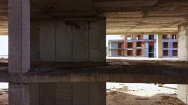 Tamamlanmamış bir bina, güneş ışığının beton sütunlara yansıdığı ve renkli tuğla duvarların parladığı terk edilmiş bir bina. Toz havada dans eder, mistik bir atmosfer yaratır..