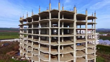 Beton sütunlar gökyüzüne yükselir, yemyeşil tarlalar ve uzak tepeler tarafından çerçevelenir, modern inşaatın ilerlemesini gözler önüne serer..