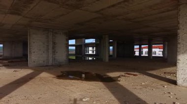 Paslanmış kirişlerin ve su birikintilerinin güneş ışığını yansıttığı boş bir inşaat alanındaki toz dansları. Gölgeler çatlamış beton sütunlar boyunca uzanıyor, kayıp potansiyeli ve unutulmuş hayalleri ortaya çıkarıyor..