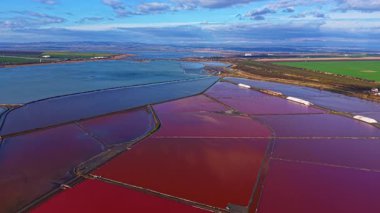 Gün batımı geniş tuz düzlüklerine altın ışık saçarken, nefes kesici renkler gökyüzünü dolduruyor. Canlı kırmızı ve dingin mavilerden büyüleyici bir desen yaratıyor. Doğanın paleti ihtişam sergiliyor.